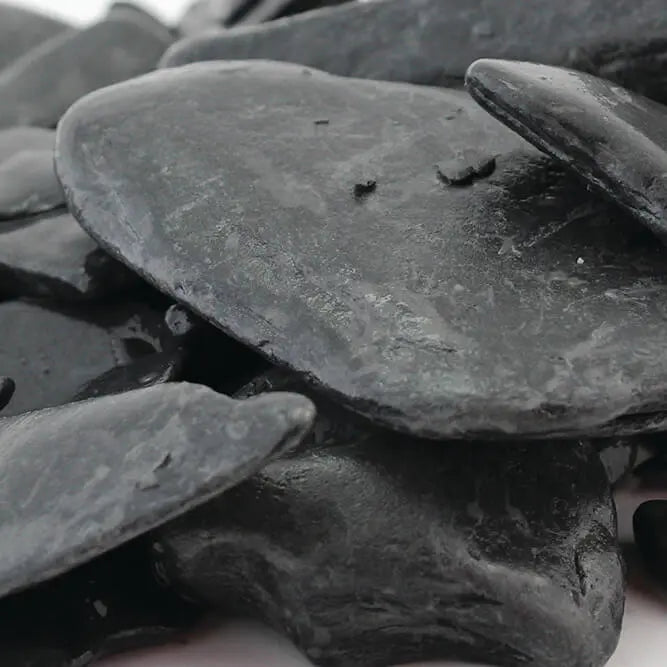 Close-up of wet black tumbled slate gravel 30-50mm highlighting smooth texture and dark shine, perfect for UK garden borders and modern landscaping designs.