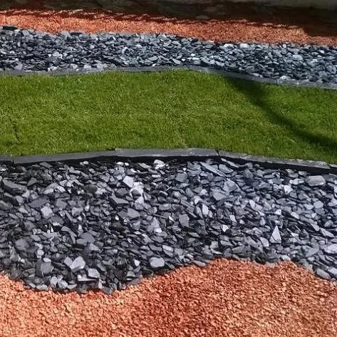 Black slate gravel 30-60mm used in UK garden landscaping alongside red gravel and grass for modern decorative contrast.