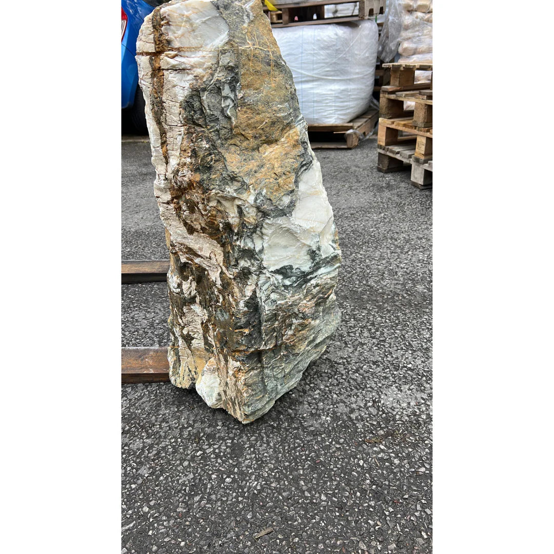 Natural stone monolith surrounded by garden pebbles and gravel, creating an elegant outdoor focal point.