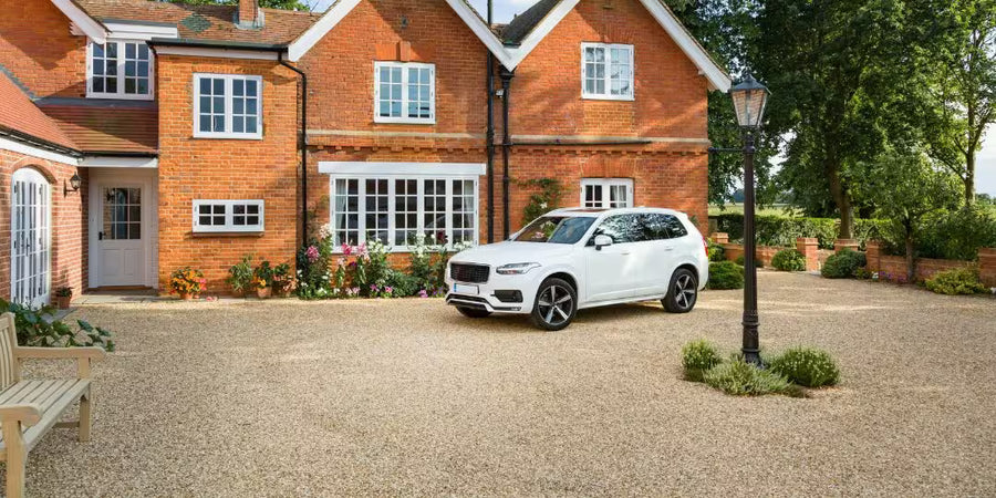 Decorative gravel driveway with a white car parked outside a house