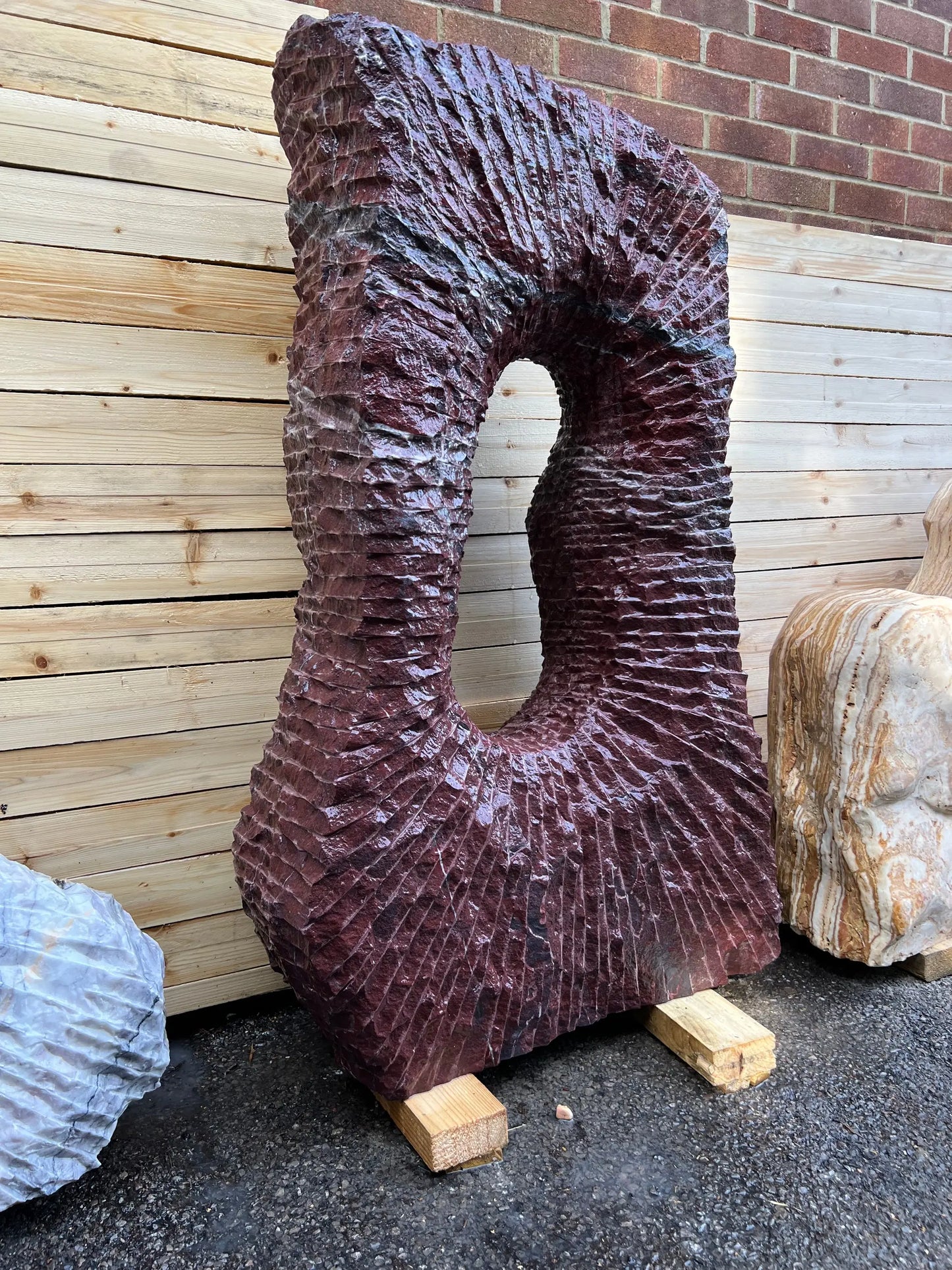 Unique one of, Onyx garden sculpture showcasing natural pink textures, complementing gravel and pebble features.