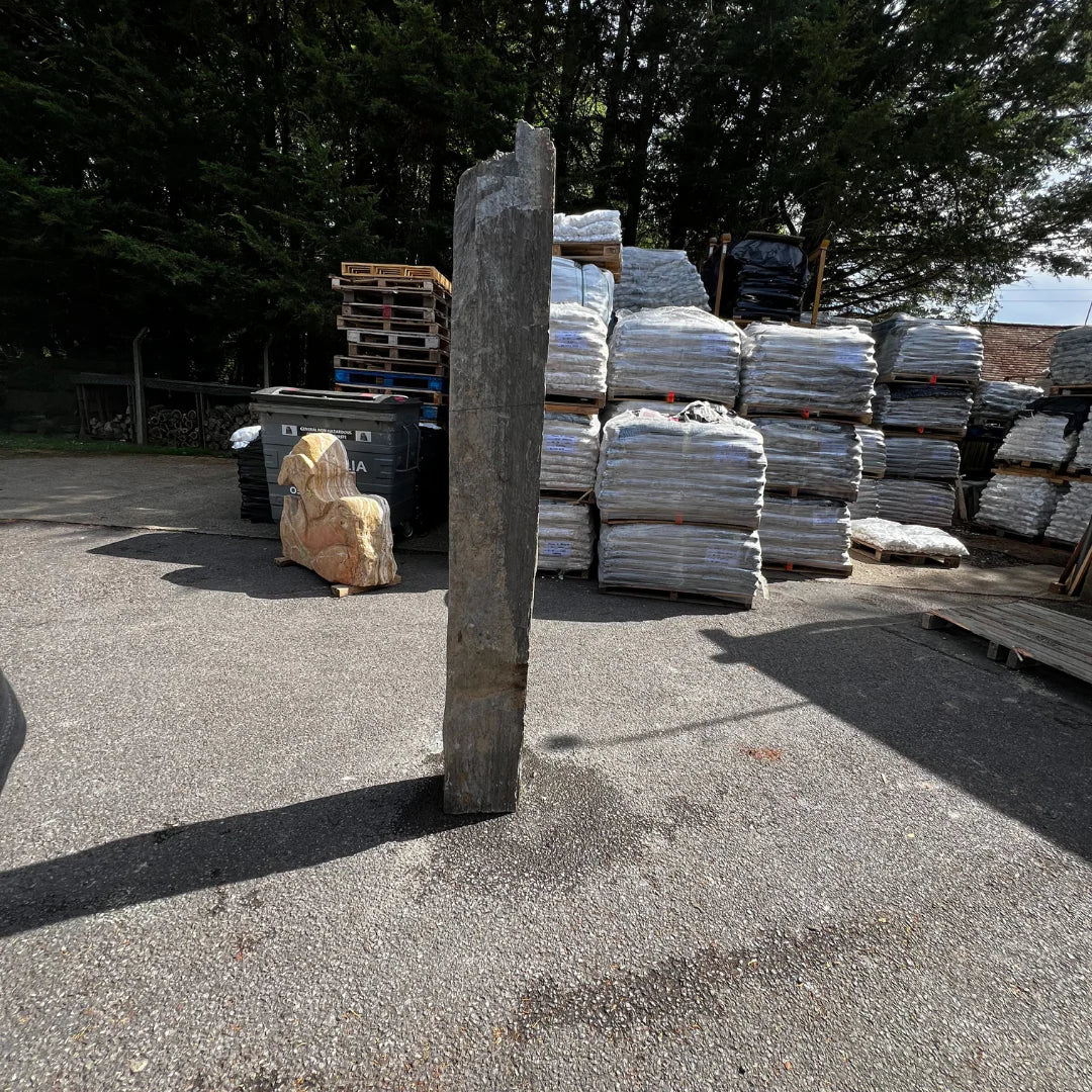 Garden pebbles and gravel arranged around a vertical natural stone monolith for a balanced outdoor display.