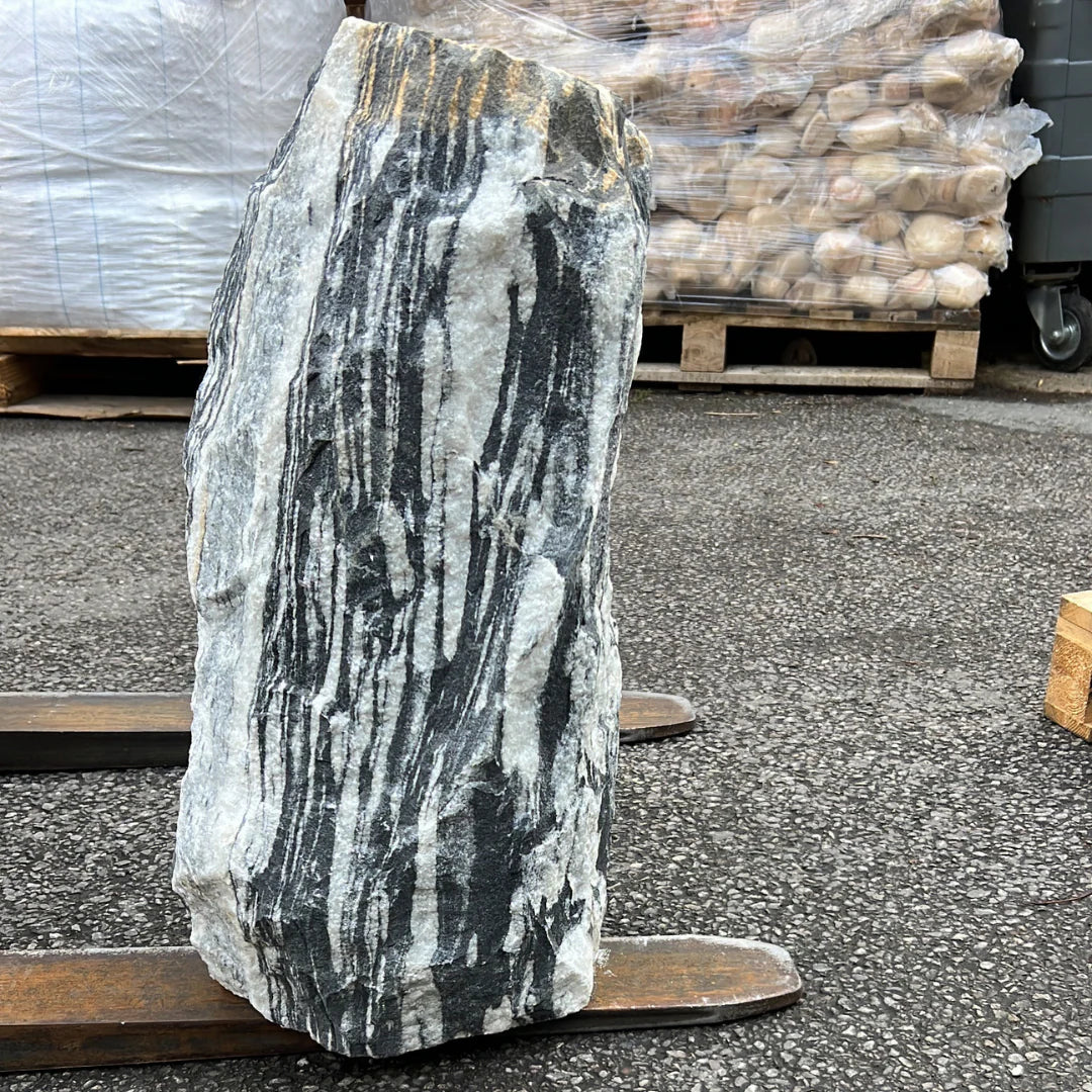 Striped grey natural stone monolith standing on a wooden pallet, perfect for UK garden and landscape design.