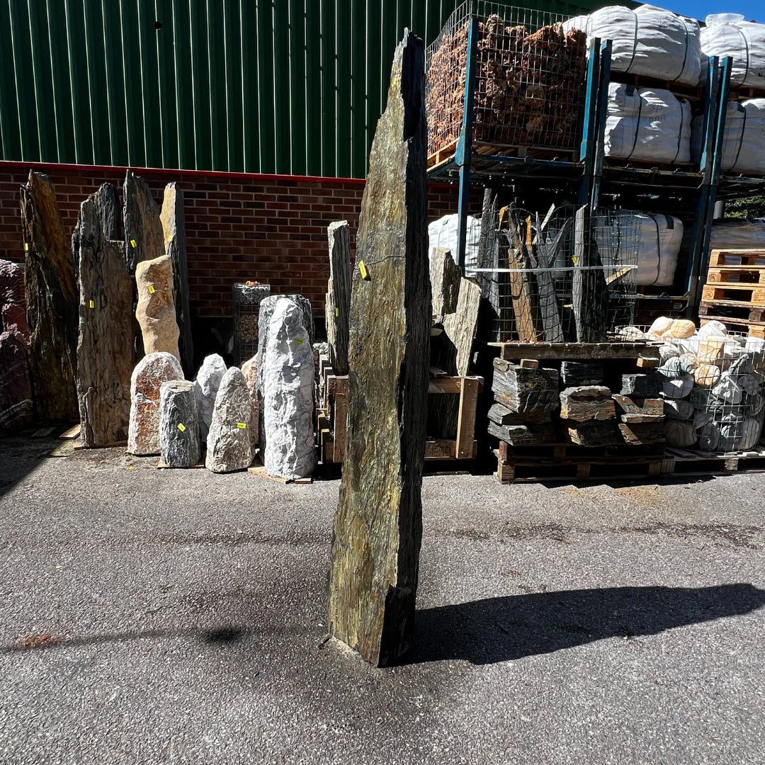 Tall outdoor monolith displayed on gravel surface, creating a dramatic focal point in landscaped garden areas.